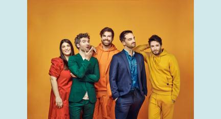 Die fünf Unduzos, darunter eine Frau und vier Männer, befinden sich vor einem gelben Hintergrund und tragen alle Kleidung in unterschiedlichen Farben. Sie schauen fröhlich in verschiedene Richtungen und wirken wie eingeschworenes Team.