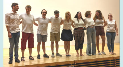 Die neun Sängerinnen und Sänger von Melodic Marketplace stehen auf einer Bühne.